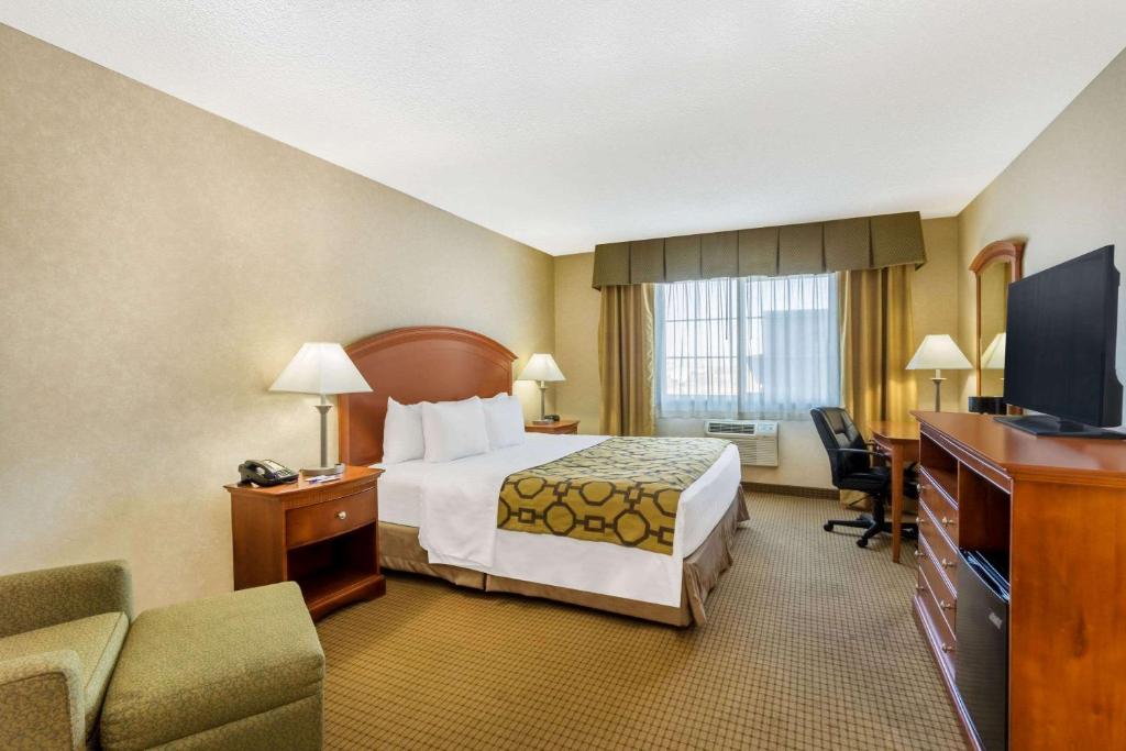 a hotel room with a bed and a television at Baymont by Wyndham Fort Morgan in Fort Morgan