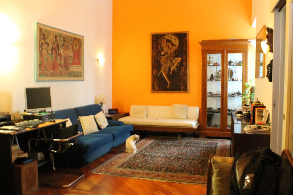 ローマにあるB&B&Courtesyの青いソファとオレンジ色の壁が備わるリビングルーム