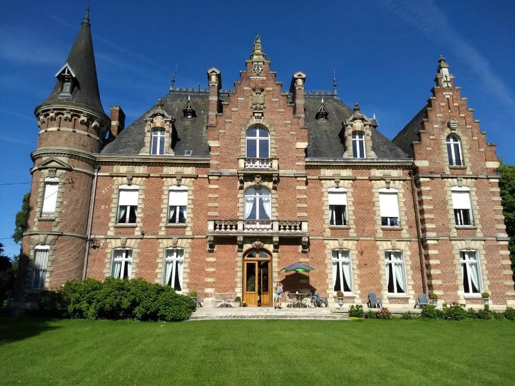 een groot bakstenen gebouw met een groen gazon ervoor bij Château des marronniers in Baizieux