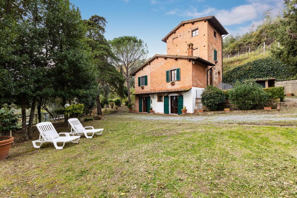 two white chairs sitting in the yard of a building at Tuscany Holiday Concierge-Podere Torre degli Ulivi in Palaia