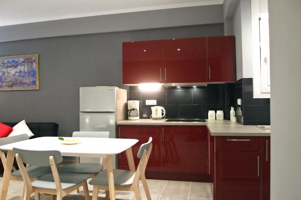 a kitchen with red cabinets and a white table and chairs at Ideally Situated Corfu Old Town Studio in Corfu Town