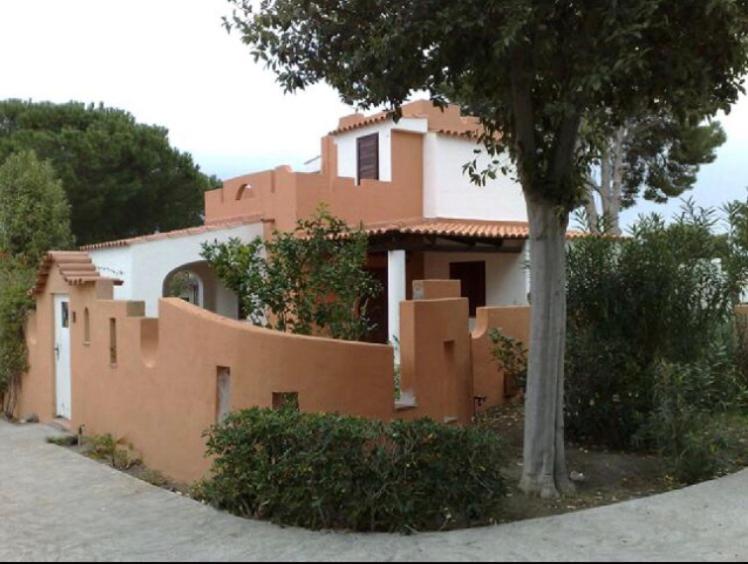 uma casa com uma árvore em frente em ALLE VIGNE CASE VACANZE em Vulcano