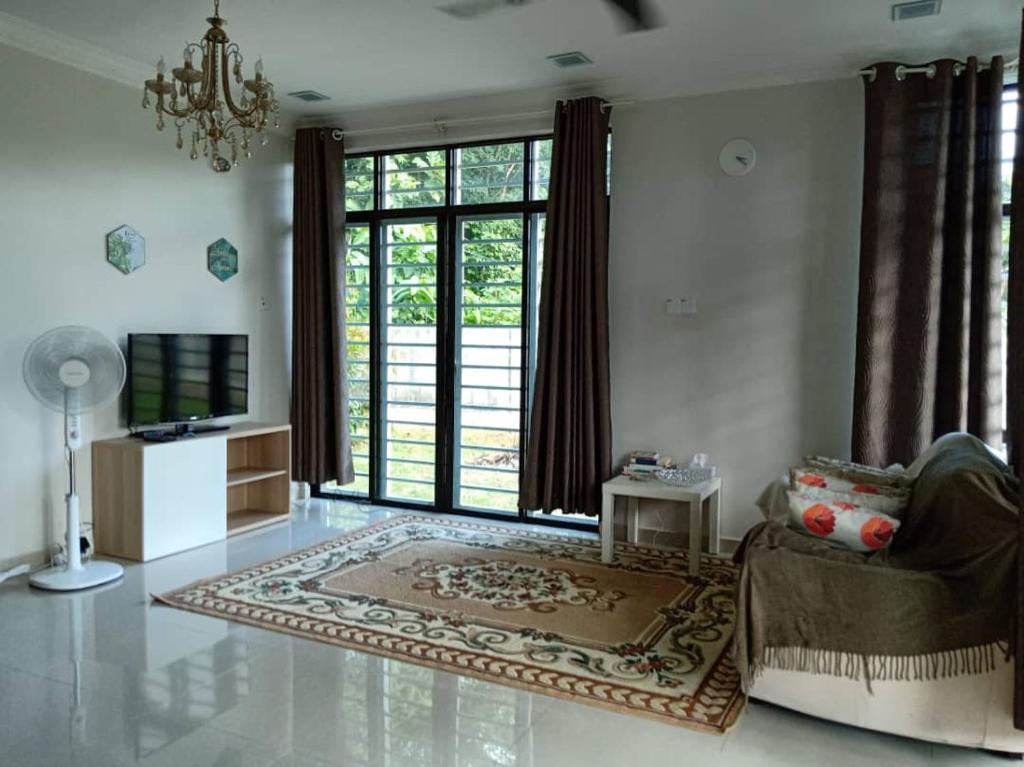 a living room with a chandelier and a couch and a television at Ajmal Homestay @ Kota Bharu in Kota Bharu