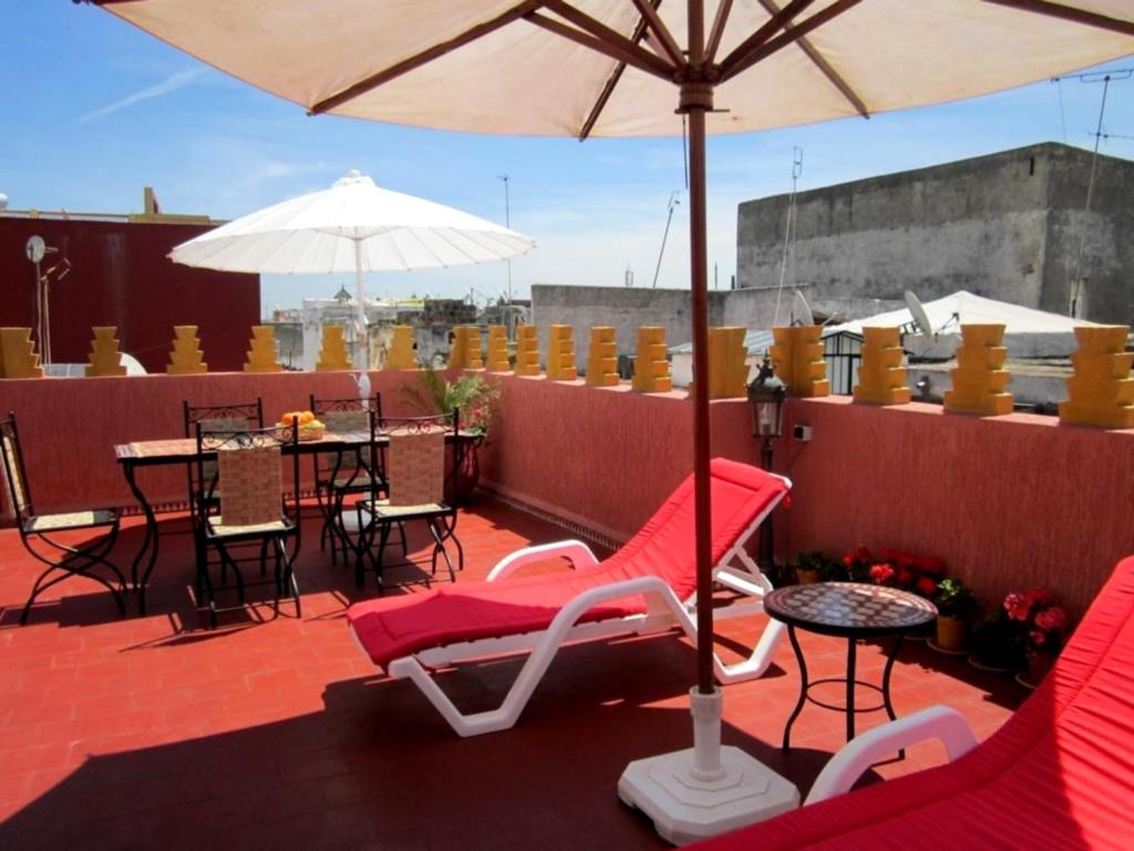 a patio with chairs and tables and an umbrella at Dar Yanis in Rabat