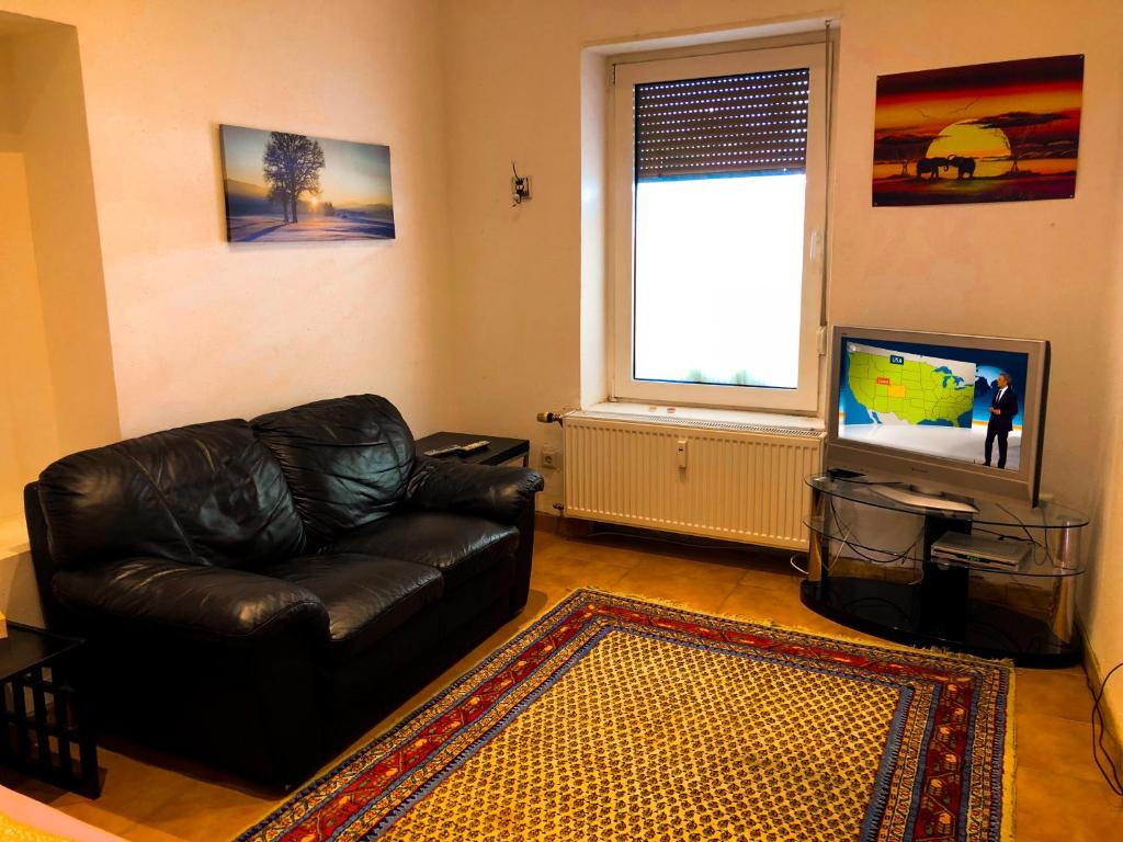 a living room with a leather couch and a television at A&S FerienwohnungenBonner str 49 in Bonn