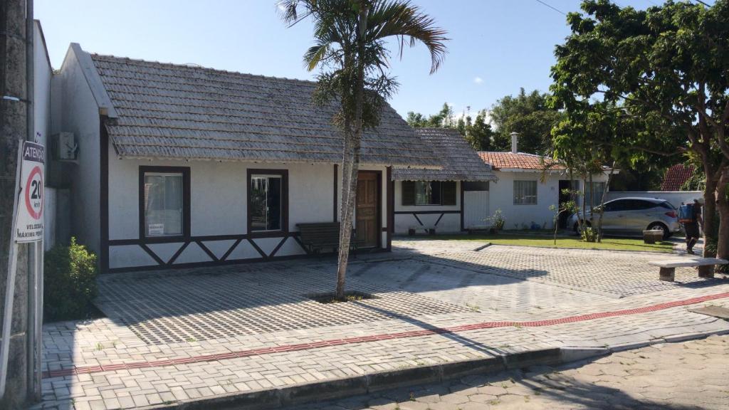 a small house with a palm tree in front of it at Baleia Branca Chalé in Porto Belo