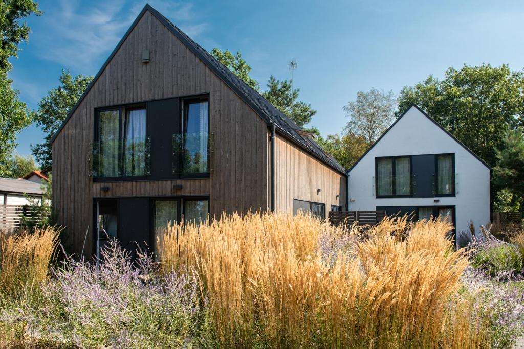 a timber house with black windows and tall grass at Skandynawskie Domy in Pobierowo