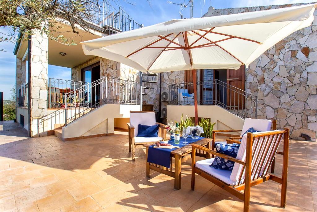 een patio met een tafel en een parasol bij Brassol Casa Vacanze Vista Mare in Alghero