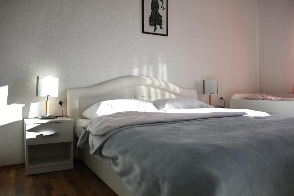 - une chambre avec un grand lit et une tête de lit blanche dans l'établissement Apartman Ćorić Posušje, à Posušje