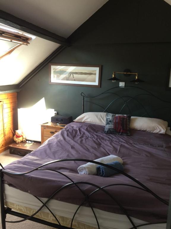 een slaapkamer met een groot bed met paarse lakens bij The Firs in Builth Wells