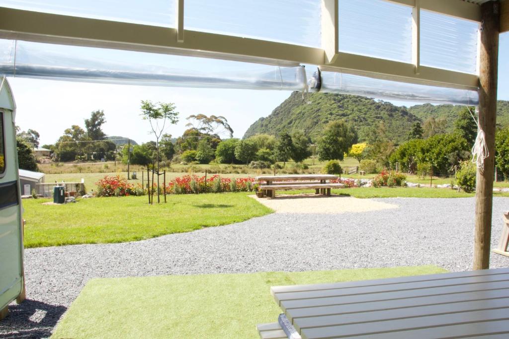 a picnic shelter with a bench and a view of a park at The Woolshed Caravans in Takaka