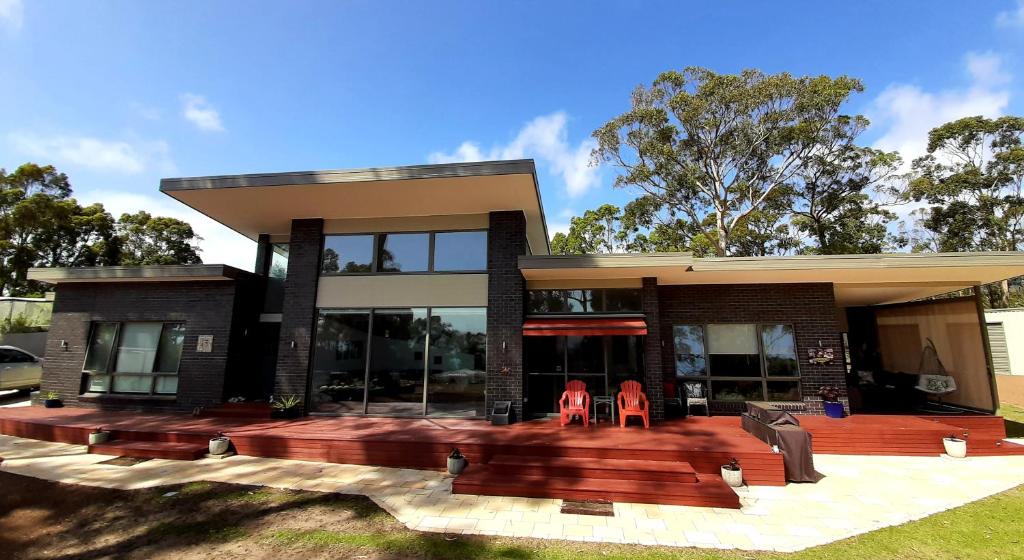 a house with two red chairs in front of it at Spring Beach Garden Retreat in Spring Beach