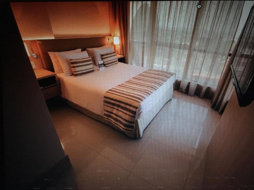 a bedroom with a large bed with pillows and a window at CULLINAN Brasilia flat particular em Hotel junto ao Shopping - SEM CAFE in Brasilia
