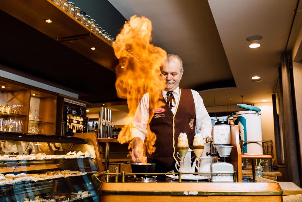 Simon - Hotel & Café في باد تاتزماندورف: رجل يطبخ الاكل في مطبخ