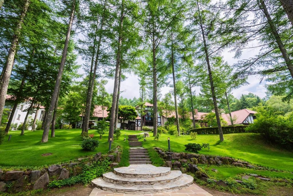 a garden with stairs and trees and houses at Tateshina Tokyu Hotel in Chino