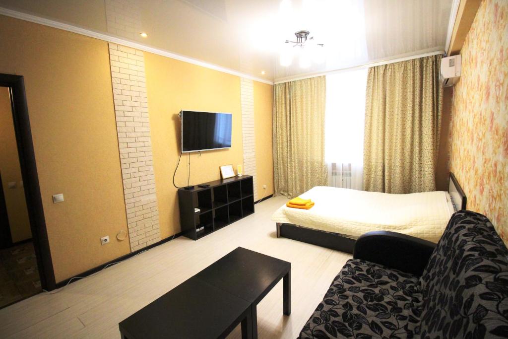 Habitación de hotel con cama, sofá y TV en Апартаменты на пр Победы OrenRoom en Oremburgo
