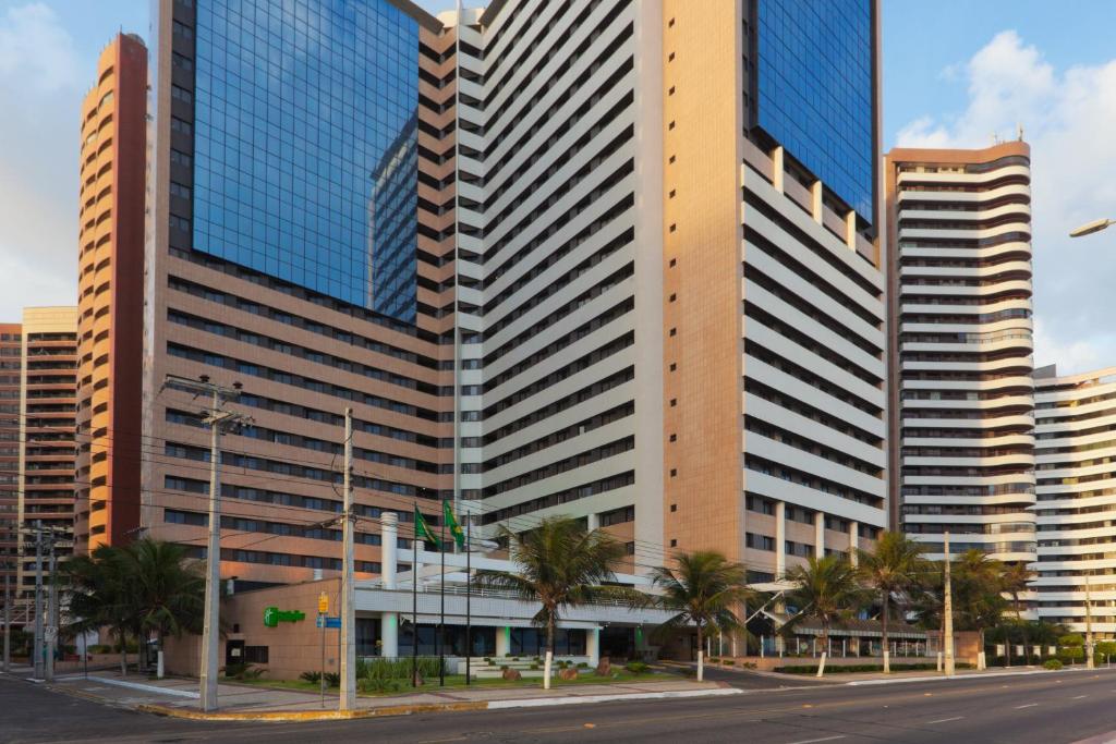 un edificio alto con palme di fronte di Holiday Inn Fortaleza, an IHG Hotel a Fortaleza