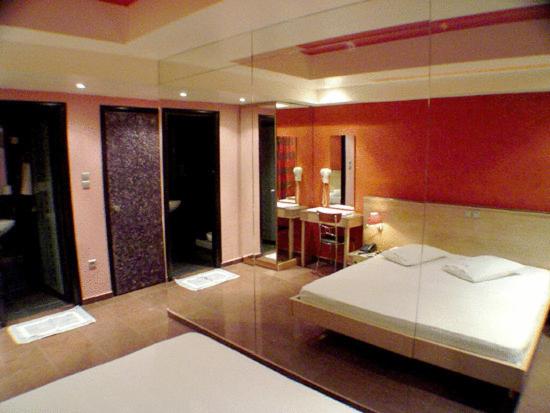 sypialnia z łóżkiem i dużym lustrem w obiekcie Hotel Niki Piraeus w Pireusie