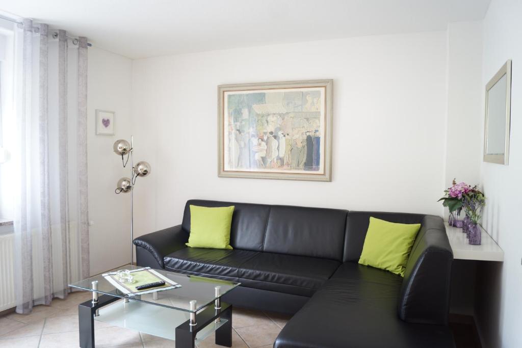 a living room with a black couch and yellow pillows at Ferienwohnung Kunkel in Kreuzau