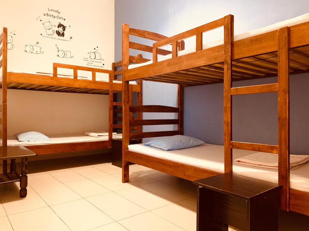 a room with three bunk beds and a desk at Prima B&B Hostel in Sandakan