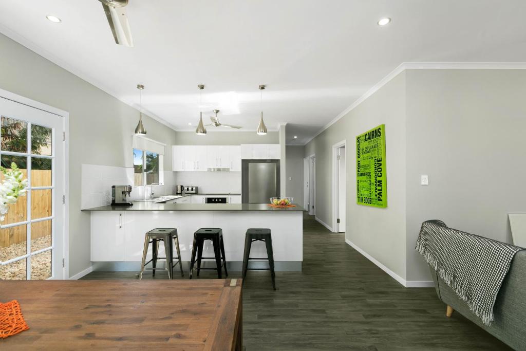 a kitchen with white walls and a table and stools at Estilo Bed and Breakfast in Cairns