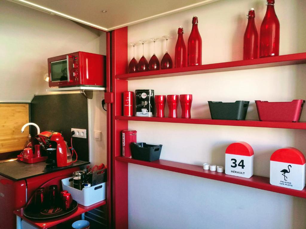 una cocina con jarrones rojos en las estanterías en Le Bâbord - petit studio moderne et bien équipé à 30 m de la mer, en Palavas-les-Flots