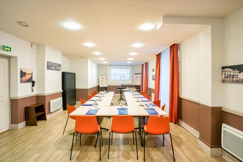a conference room with a long table and orange chairs at Campanile Orléans Centre Gare in Orléans