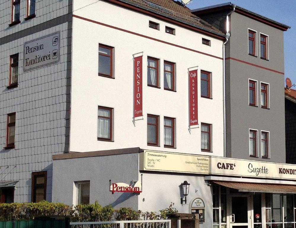 un gran edificio blanco con señales rojas. en Pension Cafe Suzette en Gotha