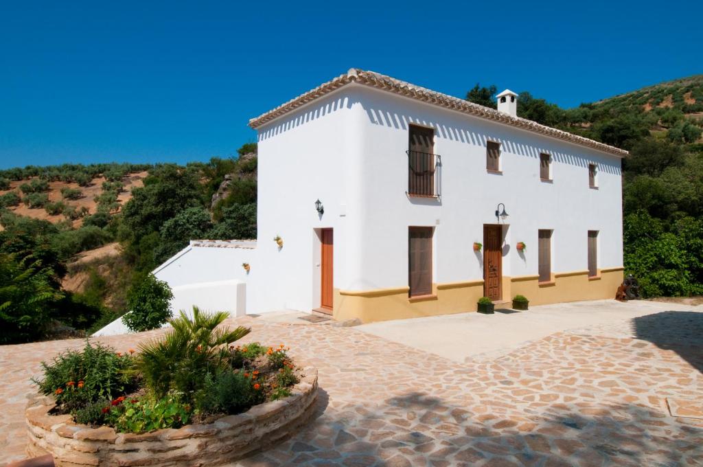 een wit huis met een heuvel op de achtergrond bij El Cortijo at Molino la Ratonera in Zagra