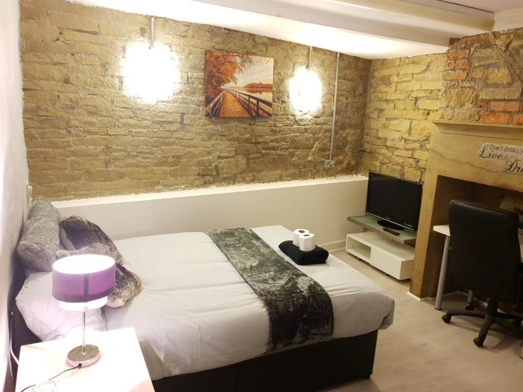 a bedroom with a bed and a tv and a brick wall at TOPAZ TOWN HOUSE No 36 in Huddersfield