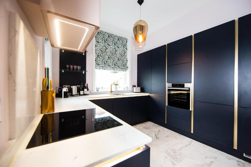 una cocina con armarios azul marino y fregadero en Maison Parfaite HG1 - 2 Luxury apartments with Parking Space - Near town centre, en Harrogate