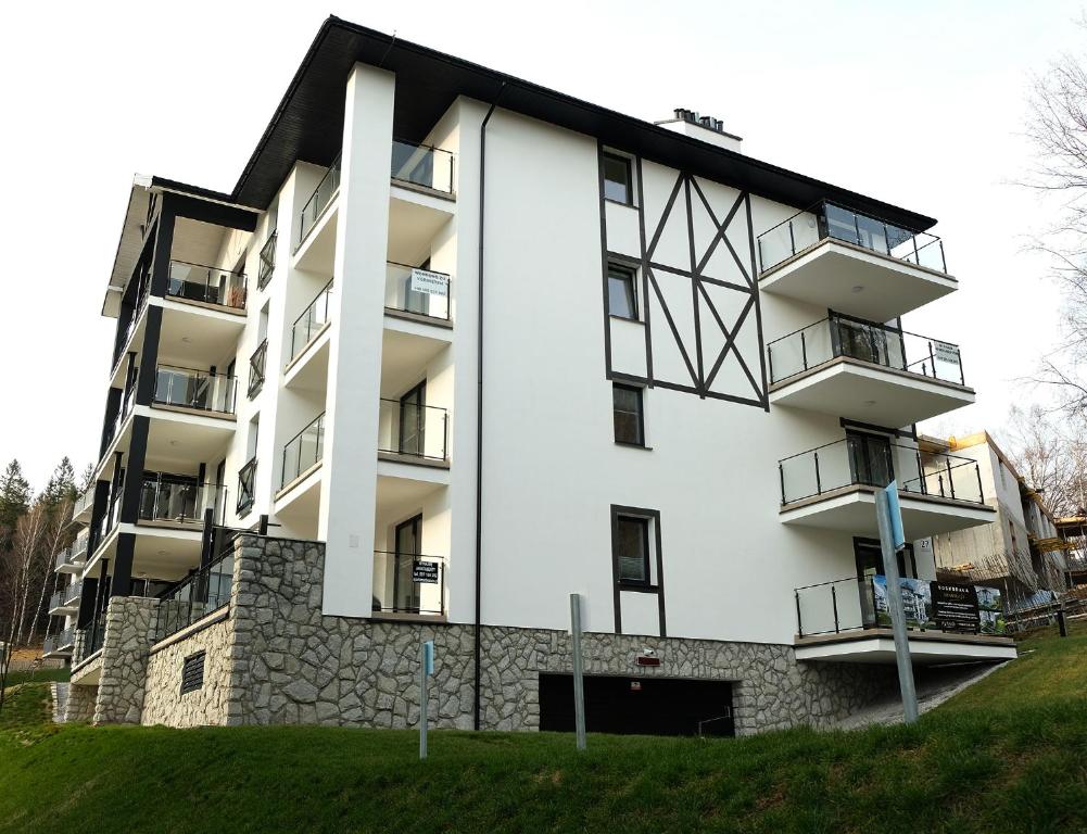 a white apartment building with a black roof at Apartamenty Rebergen w kompleksie Apartamenty Piano in Świeradów-Zdrój