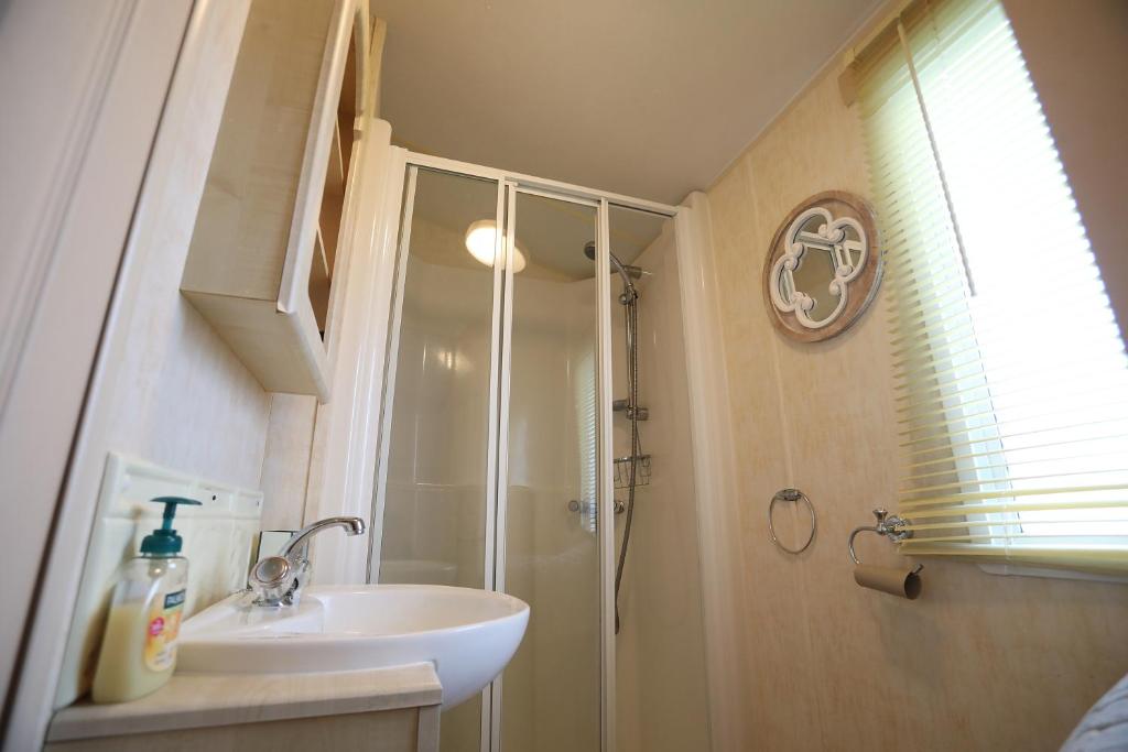 ein Bad mit einer Dusche und einem weißen Waschbecken in der Unterkunft Lovely 4 berth static caravan, Marine Holiday Park, Rhyl, Wales in Rhyl