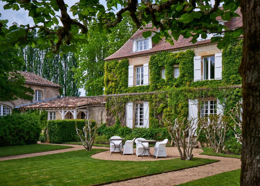 ein Haus mit Tischen und Stühlen davor in der Unterkunft Le Vieux Logis in Trémolat