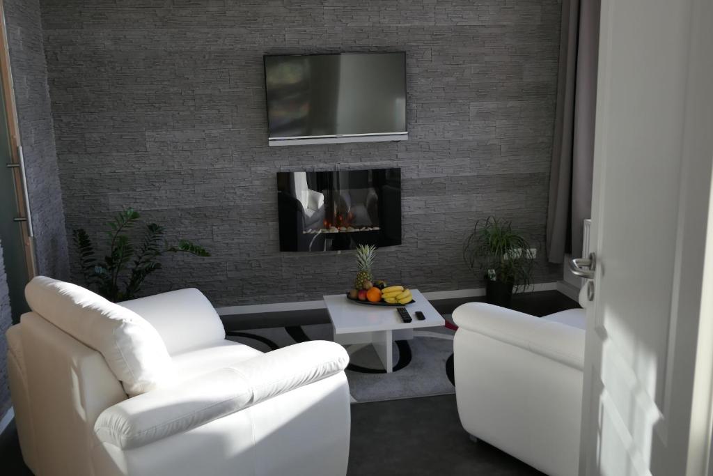 a living room with two white chairs and a fireplace at Hafenblick in Waren