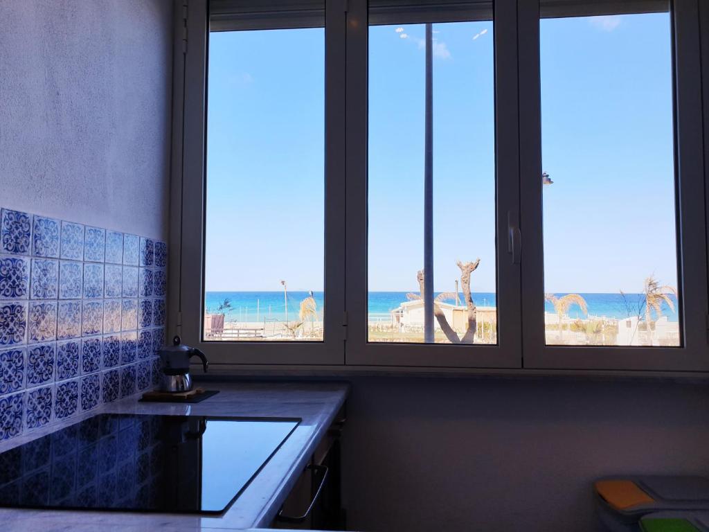 a kitchen with three windows with a view of the beach at Fronte Mare a Venetico in Venetico