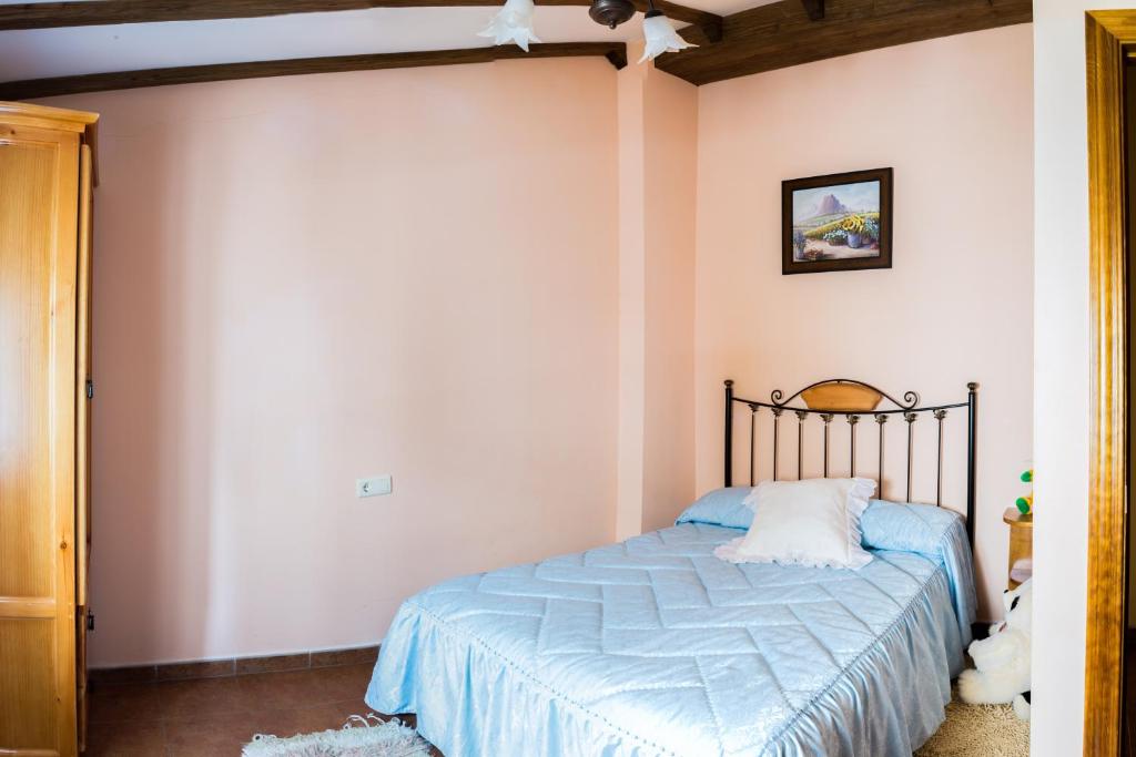 Un dormitorio con una cama con un edredón azul. en Las Calabazas, en Barrado