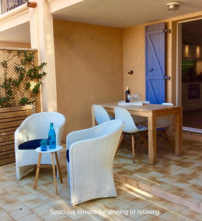 d'une terrasse avec une table et des chaises ainsi qu'une porte bleue. dans l'établissement Petit Port, à Cogolin