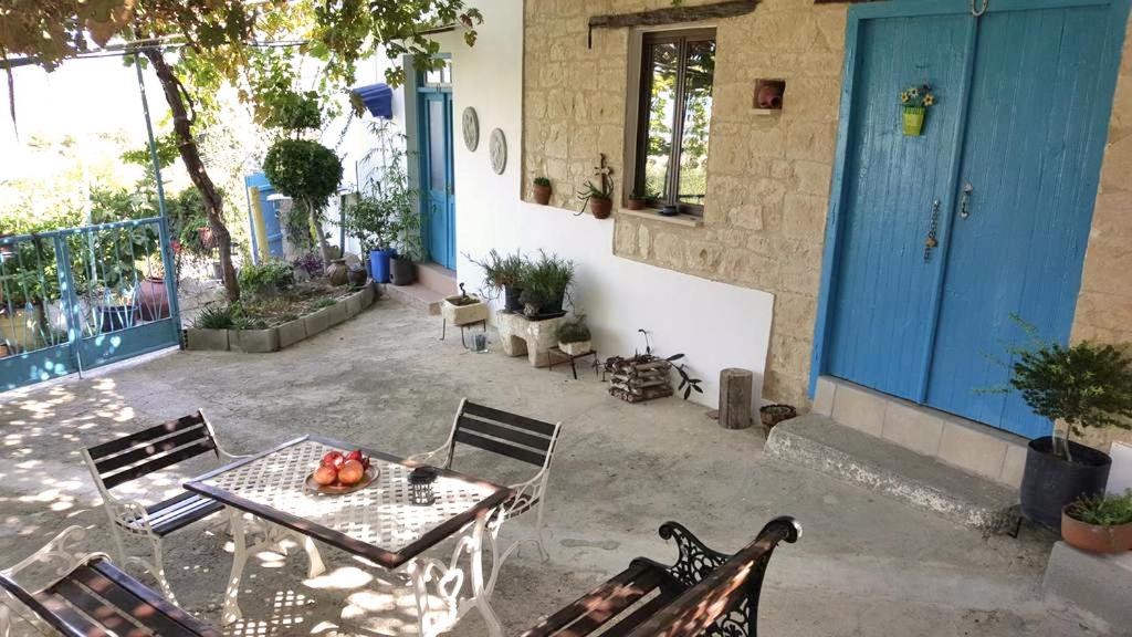 un patio con mesa y sillas y una puerta azul en Faith's Stone House, en Simou