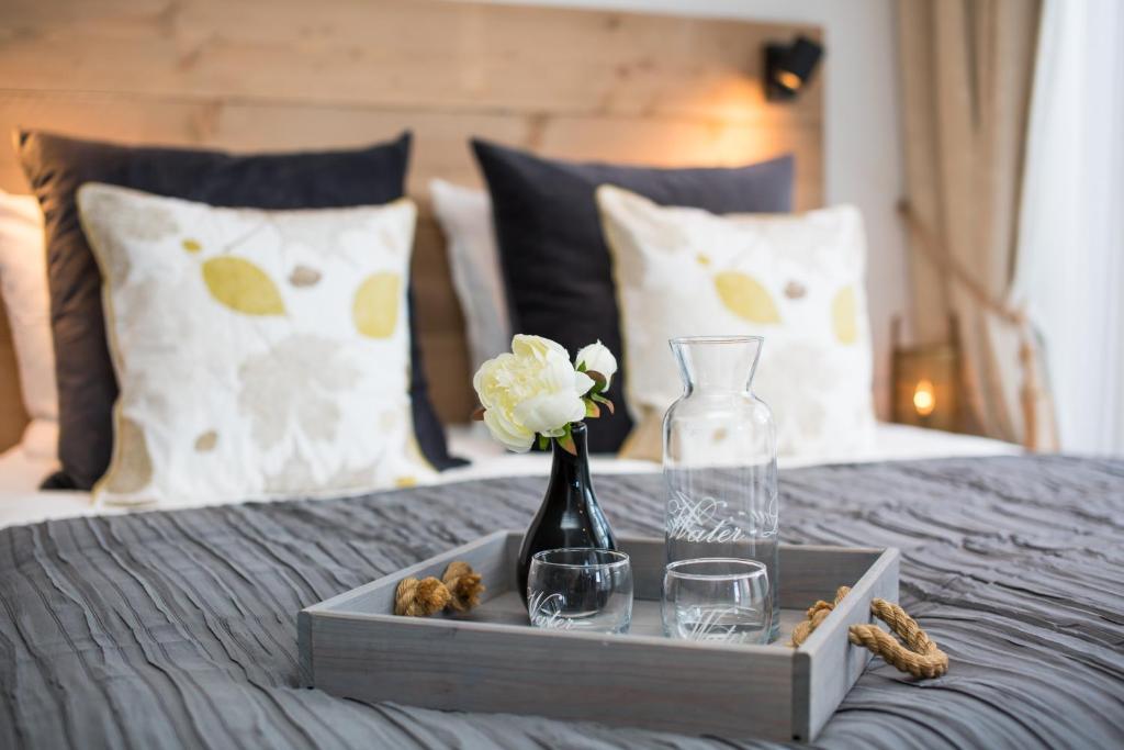 a tray with a vase and glasses on a bed at Souterrain Zuid-Duinen -Free Parking in Zandvoort