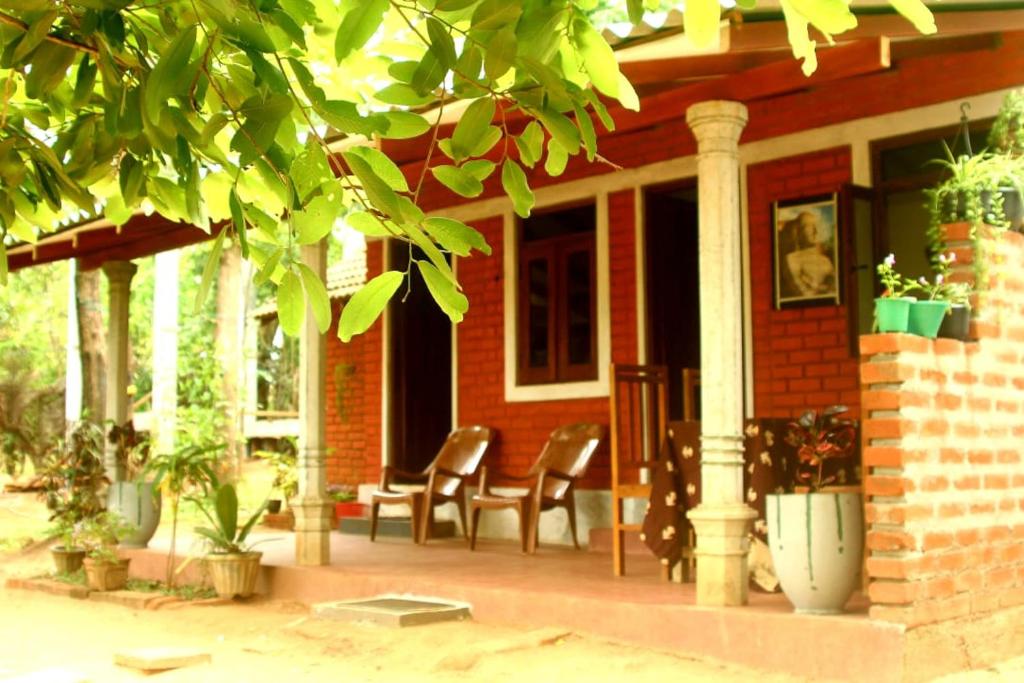 a red brick house with chairs on a porch at Angry birds homestay in Habarana