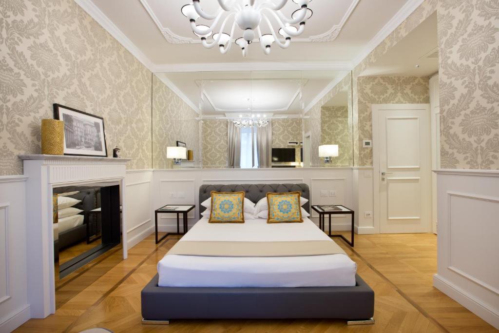 ミラノにあるドゥオーモ ルームスのベッドとシャンデリア付きの広いベッドルーム1室が備わります。