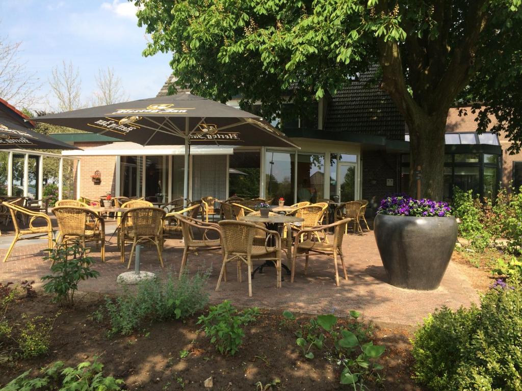 een patio met een tafel en stoelen en een parasol bij Wildenborcherhof in Vorden