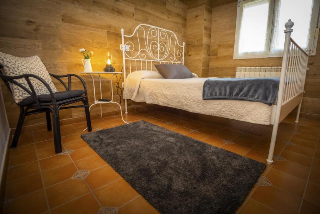 a bedroom with a bed and a chair and a window at Apartamentos Pumarin in Santa Marina