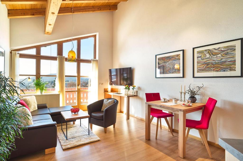 ein Wohnzimmer mit einem Tisch und roten Stühlen in der Unterkunft Landhaus Florian in Bodenmais