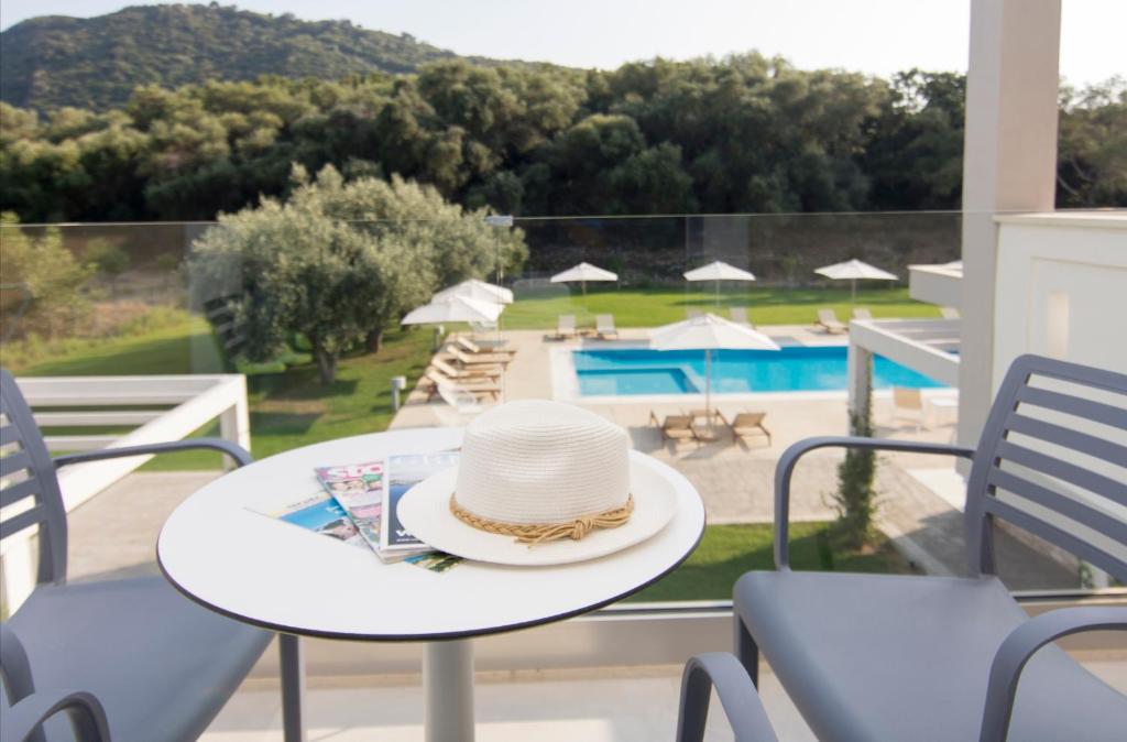 un sombrero sentado en una mesa en un balcón con piscina en Olivista Boutique Hotel, en Perdika