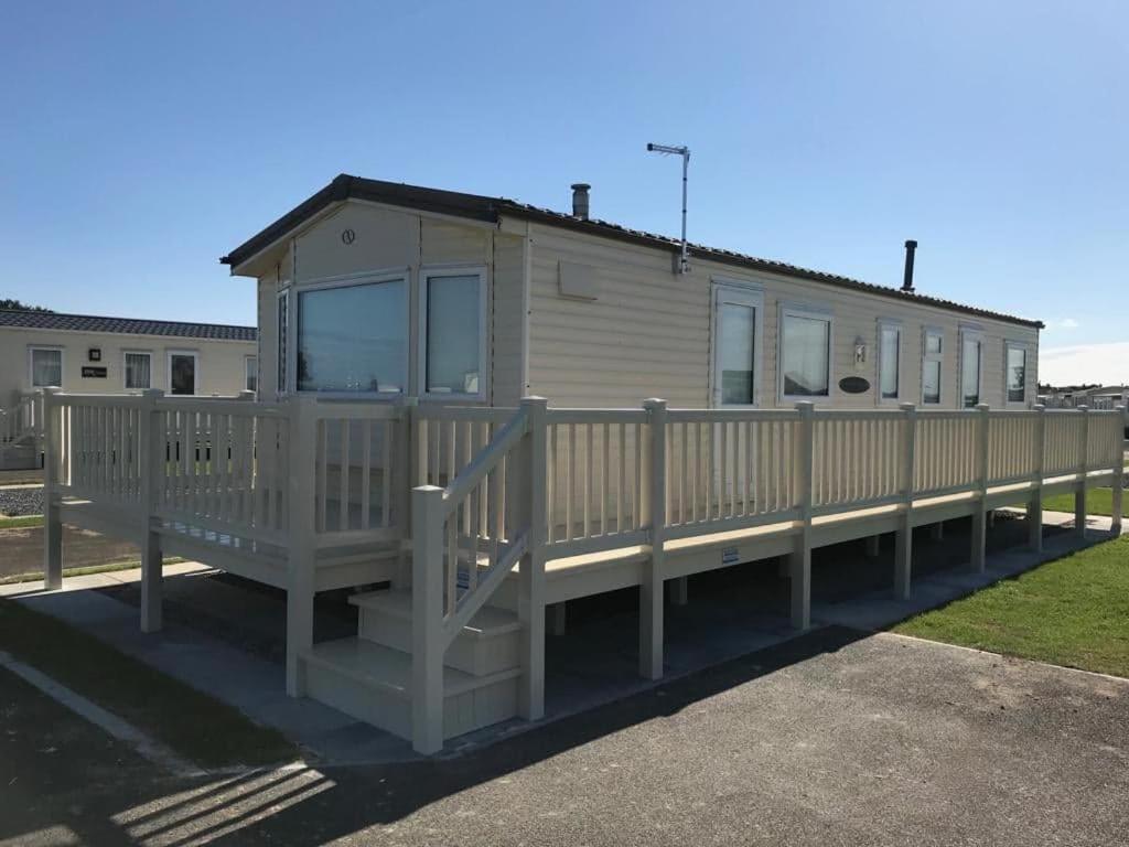 a mobile home with a porch and a fence at PALM GROVE 48 in Chapel Saint Leonards