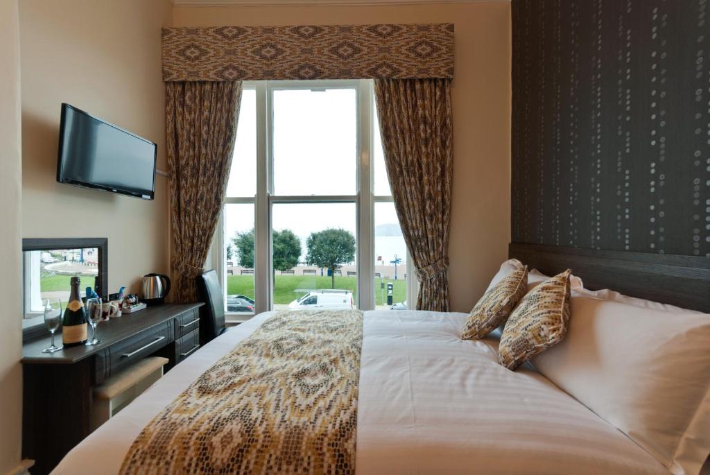 a bedroom with a large bed with a window at Lauriston & Lawton Court Hotel in Llandudno