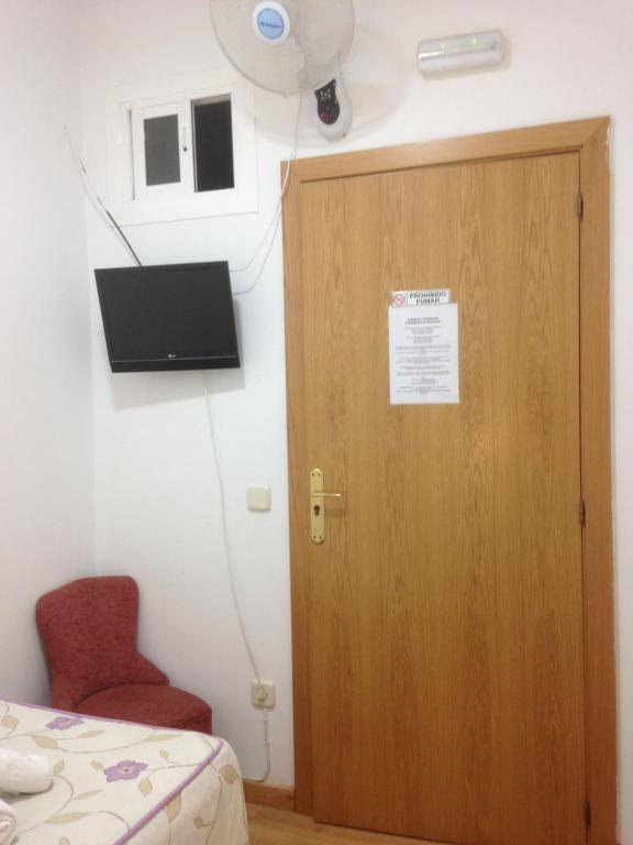 Habitación con puerta de madera y silla roja. en Hostal Nersan2, en Madrid