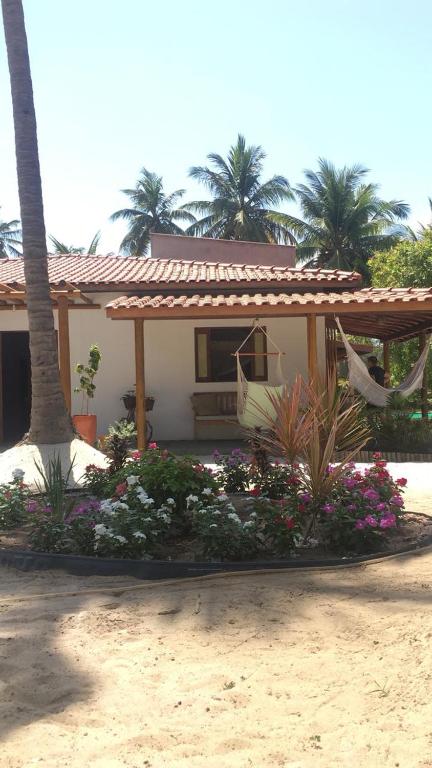 a house with a flower garden in front of it at Recanto Verde - Praia de Santo Antônio in Diogo